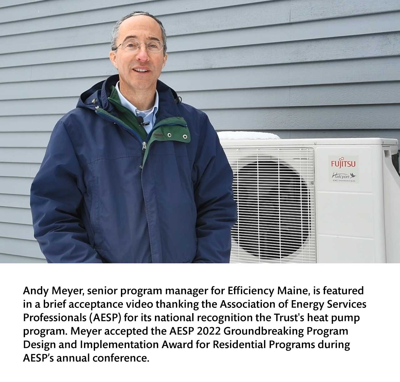 Andy Meyer, senior program manager for Efficiency Maine, posing for an acceptance video outside next to a heat pump.