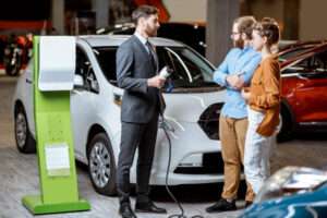 A couple buying an electric vehicle from a car salesman.