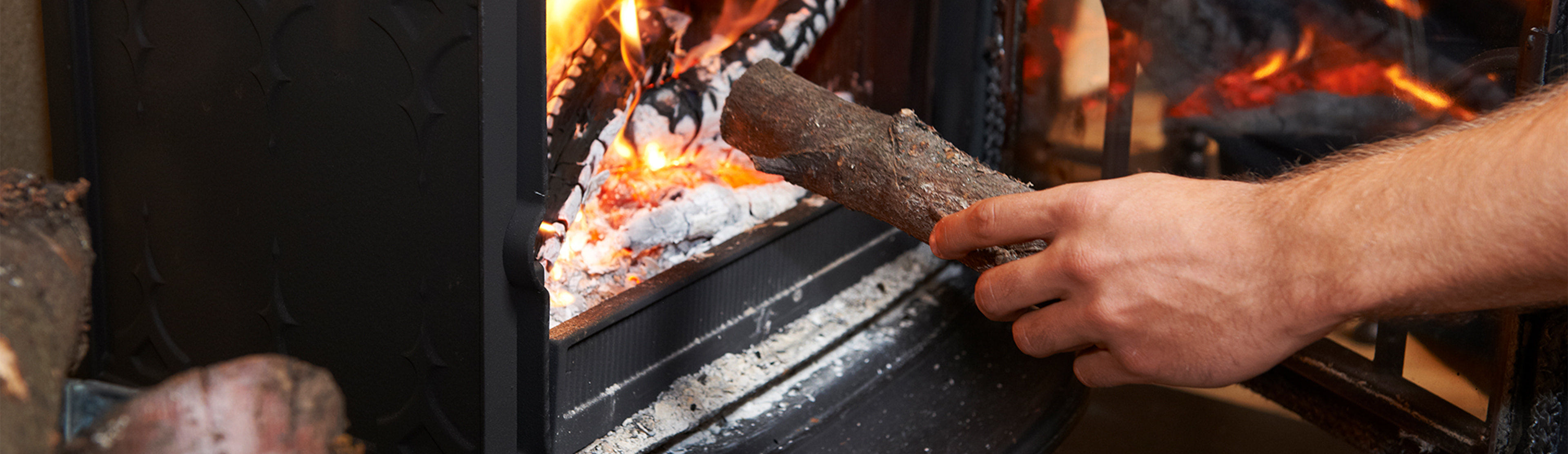 Handsome Gentleman Preparing To Slightly Increase The Intensity Of Wood Stove Fire With The Smallest Of Logs Efficiency Maine