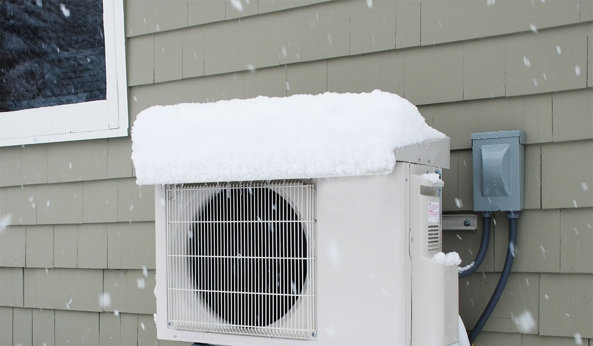 A heat pump outside covered in snow.
