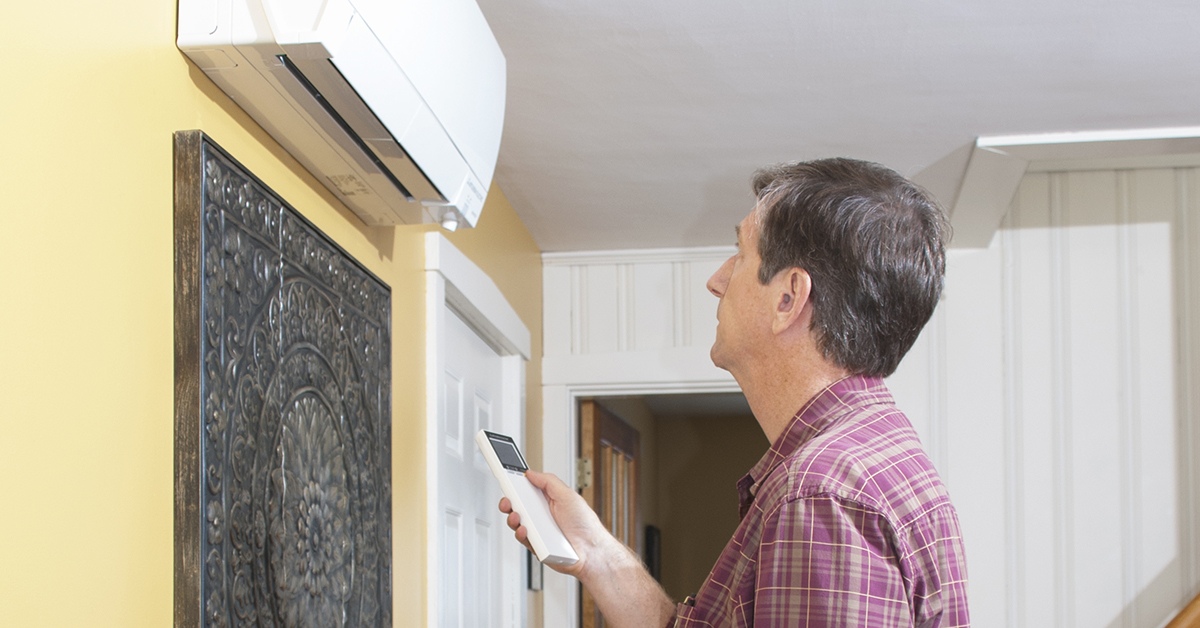 Man operating a heat pump with a remote control.